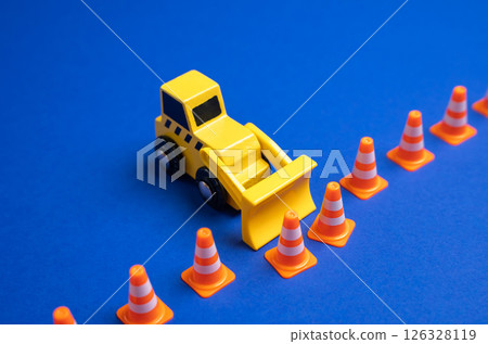 A yellow bulldozer pushes back a boundary of cones. The concept is to expand what is permitted, remove restrictions and rules. Idea of expanding freedom, lifting regulations, or redefining boundaries. 126328119