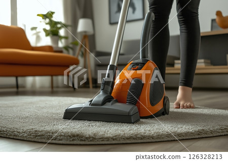 Cheerful person vacuuming a modern living room with stylish decor 126328213