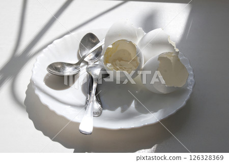 eaten soft-boiled eggs in elegant plate with teaspoons. morning meal under the sun from window 126328369