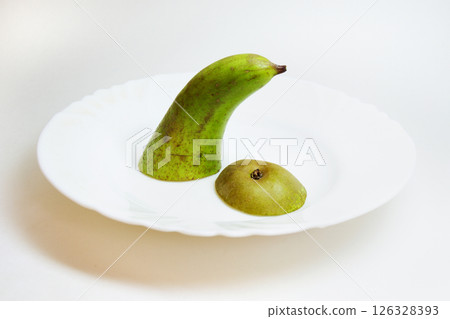 two slices of large green pear conference in small white plate. The top and bottom of a sweet varietal fruit 126328393
