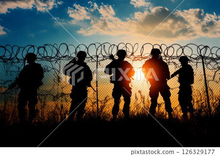 Silhouetted Figures of Soldiers Against Barbed Wire Fence. 126329177