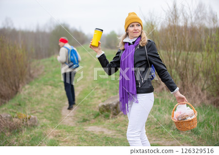 Active elderly Caucasian couple hiking with backpacks enjoying their adventure. They are getting ready for a picnic. Active elderly Caucasian couple hiking with backpacks enjoying their adventure. They are getting ready for a picnic. 126329516