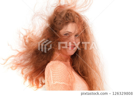 A woman with long, curly hair is smiling and posing for a picture. Concept of confidence and self-assurance, as the woman's hair is unkempt and wild, yet she is still smiling A woman with long, curly hair is smiling and posing for a picture. Concept of confidence and self-assurance, as the woman's hair is unkempt and wild, yet she is still smiling 126329808