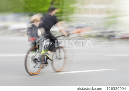 Man riding bicycle with little girl in helmet in child seat bicycle behind father, outdoors family leisure activity, healthy lifestyle 126329904
