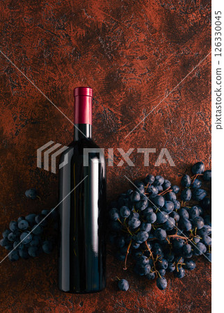 Blue grapes and bottle of red wine on a brown vintage background. Blue grapes and bottle of red wine on a brown vintage background. 126330045