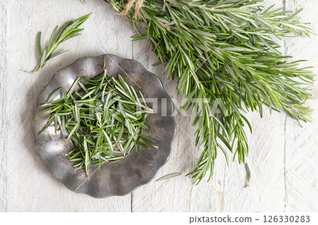 Fresh green rosemary sprigs on a plate on white rustic table top view. Aromatic herb for culinary 126330283