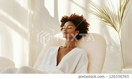 Serene woman relaxing in comfortable armchair at spa retreat 126330763