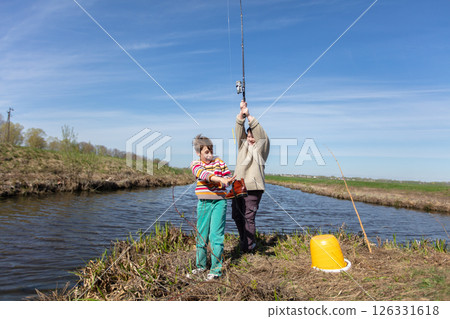 Funny fishing. Two of the boy's friends hooked an old shoe with a fishing rod and are laughing. Funny fishing. Two of the boy's friends hooked an old shoe with a fishing rod and are laughing. 126331618