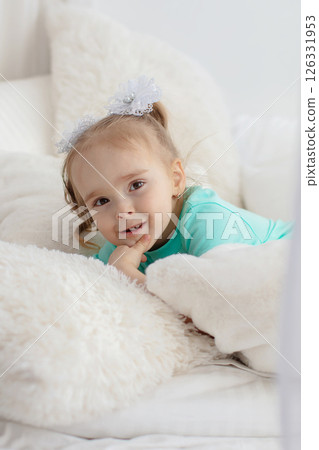 Little girl in a green shirt on white pillows. Little girl in a green shirt on white pillows. 126331953