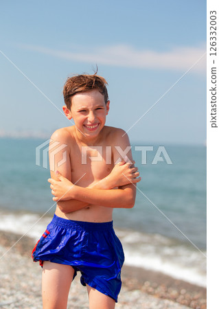 Funny boy in wet shorts on the beach. He is frozen. 126332003