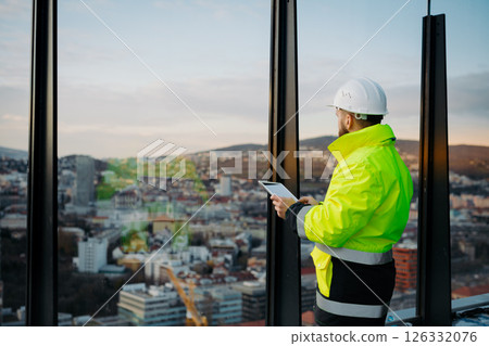 Engineer overseeing city construction project, reading documentation. Engineer overseeing city construction project, reading documentation. 126332076
