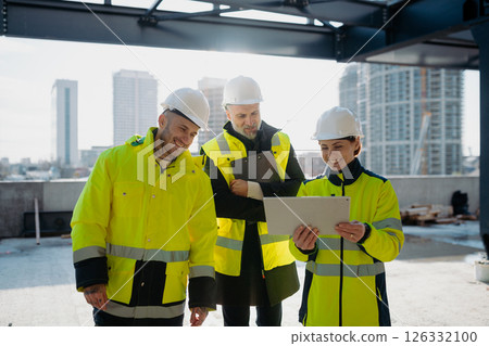 Team of engineers and construction workers inspecting building progress. 126332100