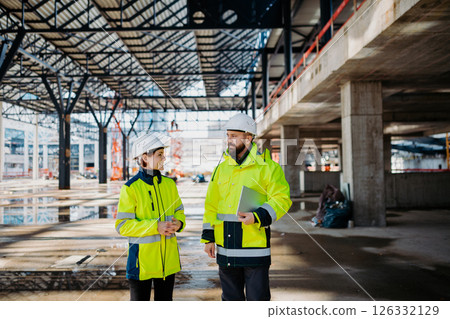Engineers discussing construction plans using a tablet on site. 126332129