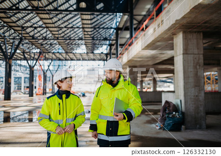 Engineers discussing construction plans using a tablet on site. 126332130