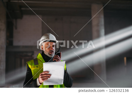 Construction foreman giving instructions over radio during building inspection. 126332136