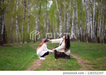 Mother and daughter are walking through a birch grove. Mother and daughter are walking through a birch grove. 126332247