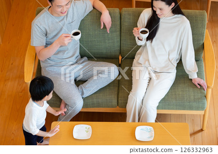 A Japanese couple relaxing with their child in the living room 126332963