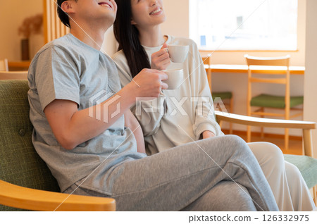 A Japanese couple relaxing on the sofa in the living room 126332975