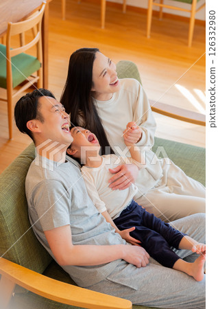 Smiling Japanese parents and children sitting on the sofa 126332980