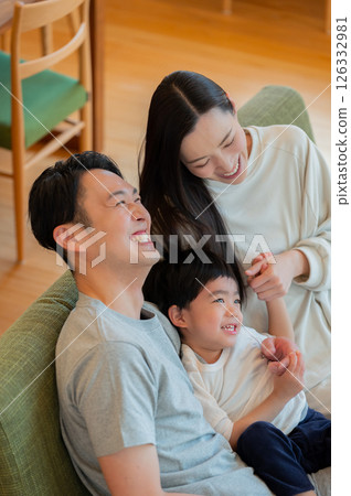 Smiling Japanese parents and children sitting on the sofa Smiling Japanese parents and children sitting on the sofa 126332981