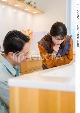 A man in work clothes inspecting kitchen equipment and a woman consulting with him 126333027