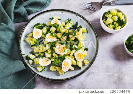 Appetizing mix of cucumbers, eggs and chives on a plate on the table 126334479