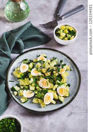 Appetizing mix of cucumbers, eggs and chives on a plate on the table vertical view 126334481