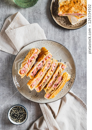 Crispy envelopes with sausage and cheese in flat bread on a plate top and vertical view 126334502