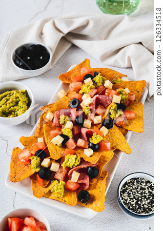 Appetizer plate with nachos, salami, cheese, tomato and black olives vertical view Appetizer plate with nachos, salami, cheese, tomato and black olives vertical view 126334518