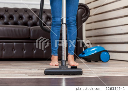 Close-up of a woman cleaning the floor with a vacuum cleaner Close-up of a woman cleaning the floor with a vacuum cleaner 126334641