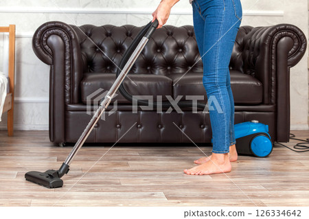 Close-up of a woman cleaning the floor with a vacuum cleaner Close-up of a woman cleaning the floor with a vacuum cleaner 126334642