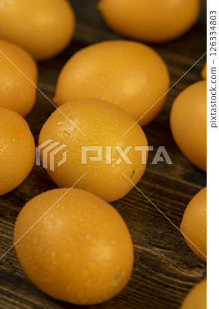 wet tomatoes of small size with soft flesh, yellow tomatoes covered with drops 126334803