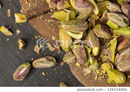 pistachios peeled from the shell, crunchy nuts, pistachios without shells, cut into small and large pieces on a board, closeup 126334860