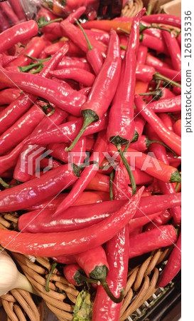 Fresh red chili peppers piled in a wicker basket 126335336