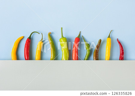 Red, green and yellow hot pepper on a blue and gray background with space for text. Flat lay. Healthy food, fresh healthy vegetables from the garden Red, green and yellow hot pepper on a blue and gray background with space for text. Flat lay. Healthy food, fresh healthy vegetables from the garden 126335826
