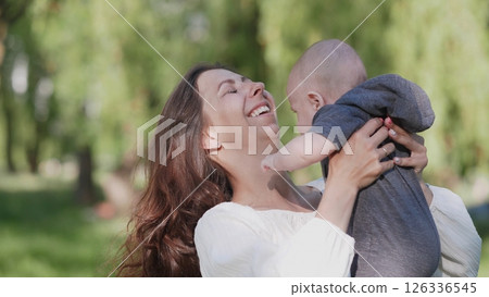 A beautiful joyful and happy mother with a small child in her arms summer portrait A beautiful joyful and happy mother with a small child in her arms summer portrait 126336545