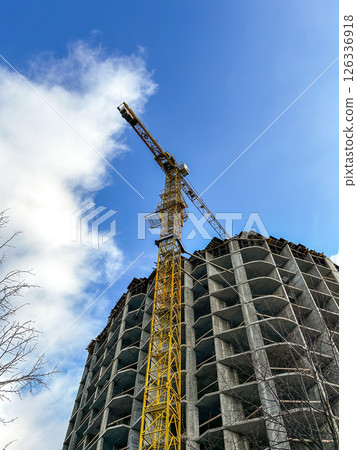 Low-angle shot of construction site with cranes of unfinished building. Perfect for real estate and urbanization topics. Low-angle shot of construction site with cranes of unfinished building. Perfect for real estate and urbanization topics. 126336918