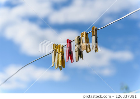 Clothespins on wire with blue sky and clouds background. 126337381