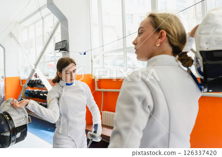 Two female fencers removing masks after match Two female fencers removing masks after match 126337420