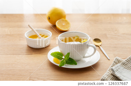 Cup of herbal tea with lemon, honey and mint on wooden tabletop with citrus fruits 126337687
