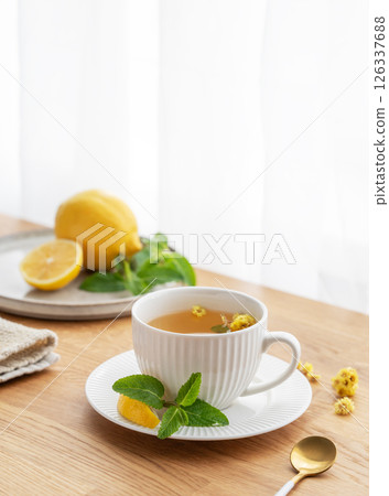 Cup of herbal tea with lemon, honey and mint on wooden tabletop with citrus fruits 126337688