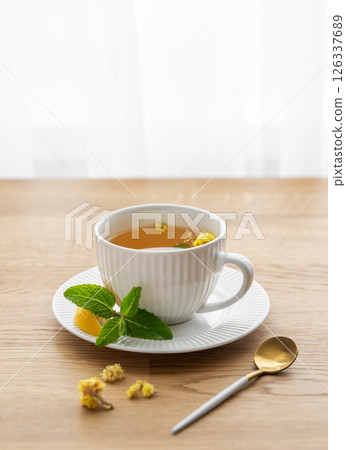 Cup of herbal tea with lemon, honey and mint on wooden tabletop 126337689