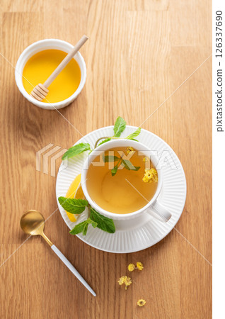 Cup of herbal tea with lemon, honey and mint on wooden tabletop with citrus fruits 126337690