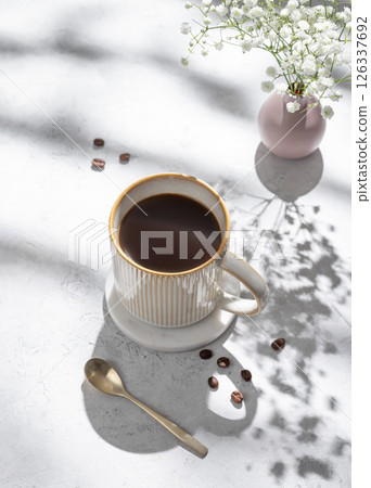Cup of freshly brewed coffee and bouquet of gypsophila on light textured background 126337692