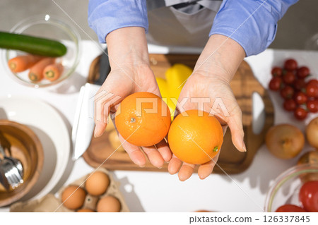 Middle-aged woman's hand holding fresh tangerines 126337845