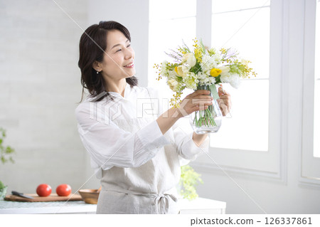 廚房裡拿著花瓶微笑的中年婦女 126337861