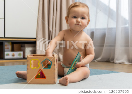 Sweet caucasian baby boy sitting on floor and playing 126337905