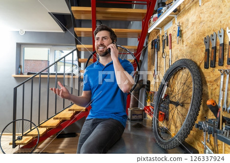 Mechanic talking on cellphone in workshop Mechanic talking on cellphone in workshop 126337924