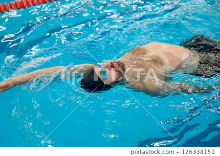 Man in black swimming cap swimming backstroke in the pool Man in black swimming cap swimming backstroke in the pool 126338151