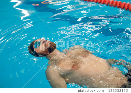 Man in swimming glasses and swimming cap spending time in a pool Man in swimming glasses and swimming cap spending time in a pool 126338153